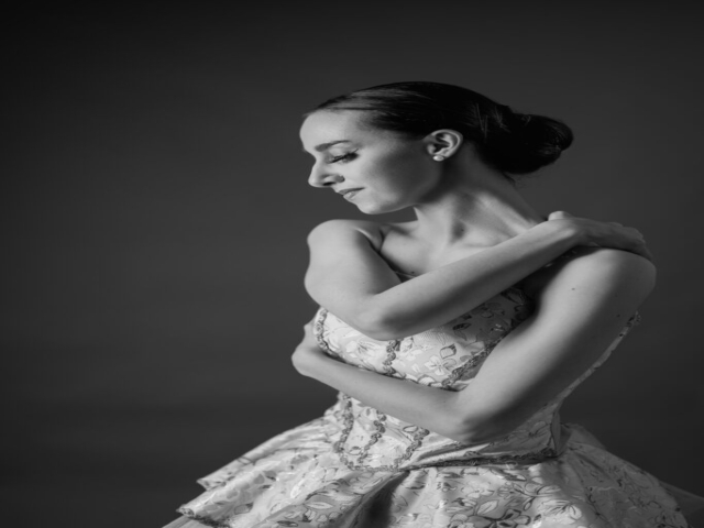 Black and white image of Erica, a ballerina. A portrait of Erica in an ivory tutu with embroidered decorations.