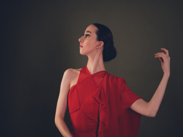 Image of Erica, a ballerina. A portrait of Erica in a red dress with train, in dance pose.