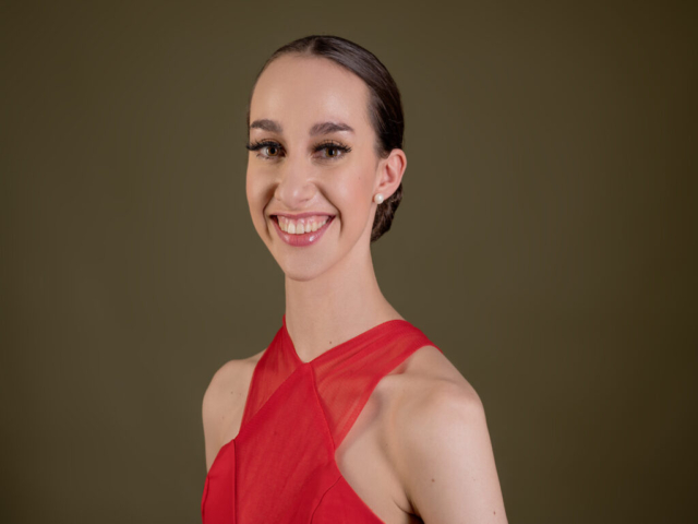 Image of Erica, a ballerina. A portrait of Erica, smiling in a red dress .