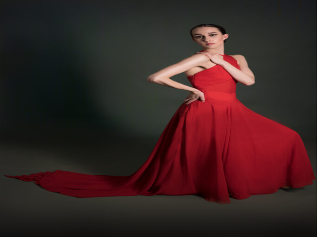 Image of Erica, a ballerina. A full length portrait of Erica in a red dress with train, in dance pose.