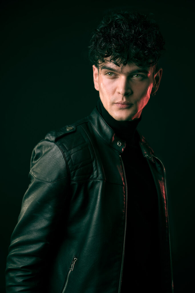 Male model in leather jacket, looking off to the side of the image