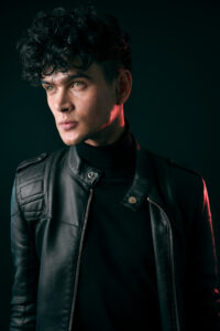 Male model in leather jacket, looking off to the side of the image