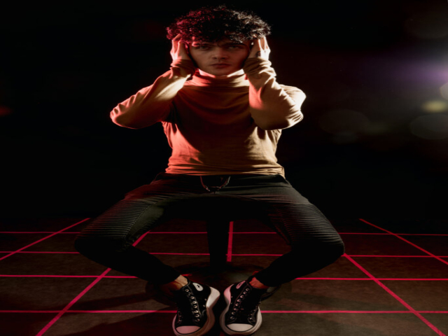 Male model sat on a stool on a retro-wave-inspired grid floor, with lens flare in the back right of the image.