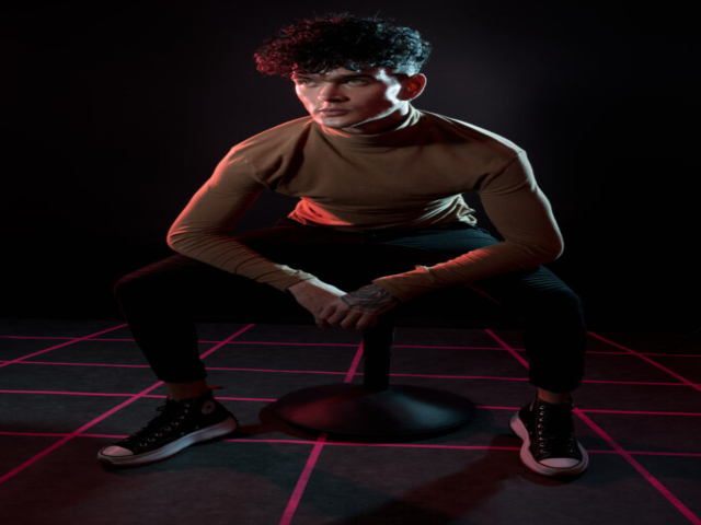 Male model sat on a stool on a retro-wave-inspired grid floor