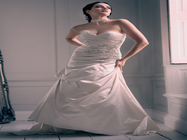 Female, caucasian model dressed in wedding gown, in a white studio against a large window